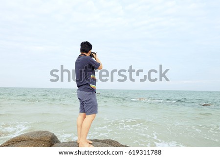 young man taking a photo bt the sea in the beach in afternoon, 