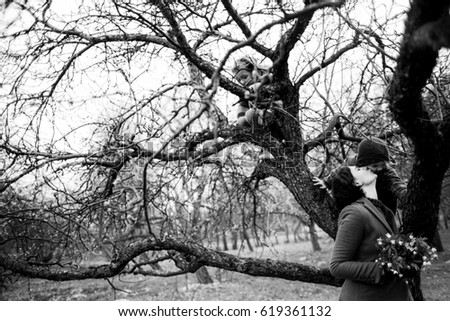 The pretty daughter sitting on the tree and mother looking at her daughter
