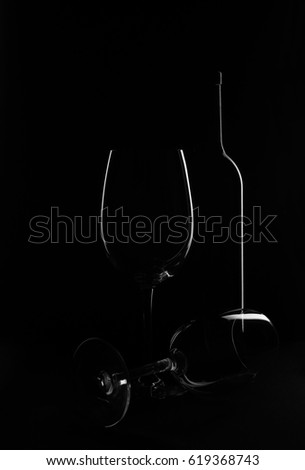 A bottle of wine on a black background with a beautiful glass
