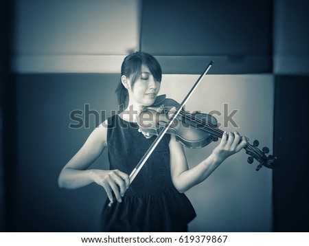 The violin teacher is showing the violin song and the technique of playing at studio music room  on stage to teach her student.in music instrument class.