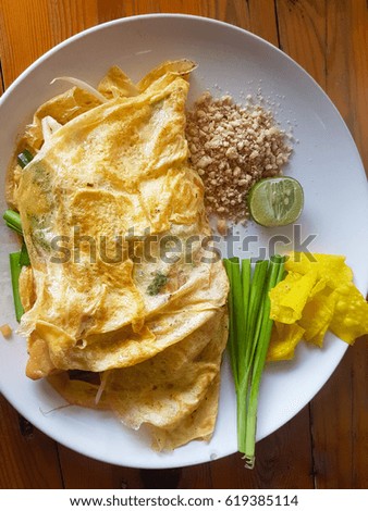 Thai food called "Pad Thai" wrapped in a thin omelet. Placed on a white plate. Take a picture from the top corner.