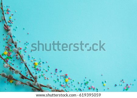 Easter background. Multicolored easter powder and willow twigs on a turquoise background. Free space