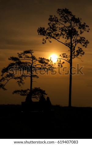 silhouette tree at sunrise with people.
