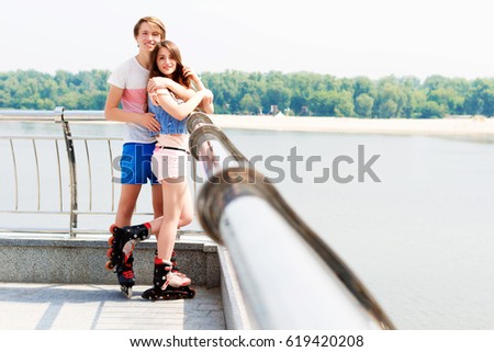 Young couple in love with roller skates hugging on the seafront