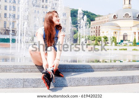 Girl wearing roller skates sitting near the fountain and smiling