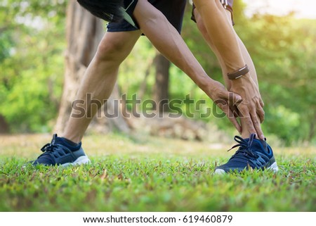 Male runner training in cold winter doing warm-up leg stretching exercise