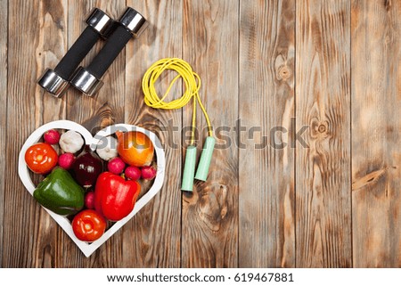 Sport and diet. Vegetables  dumbbells. Peppers, tomatoes, garlic, onions,  radishes in the heart on rustic background