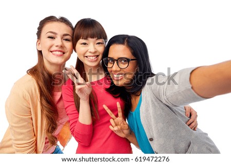 diversity, race, ethnicity and people concept - international group of happy smiling different women over white taking selfie and showing peace hand sign
