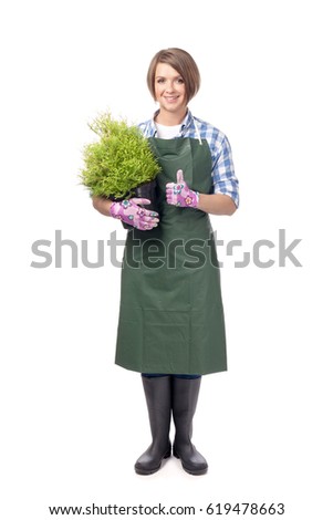 smiling woman professional gardener or florist in apron holding tree in a pot and showing thumb up isolated on white background. topiary art. gardening service, garden design and business concept