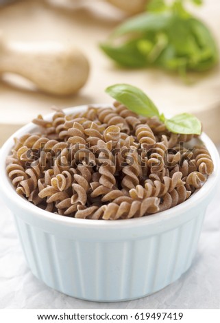 Gluten free pasta made from brown rice, uncooked in a small dish shot in window light with an out of focus background to add text or copy space.