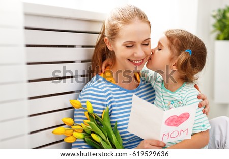 Happy mother's day! Child daughter congratulates moms and gives her a postcard and flowers tulips
