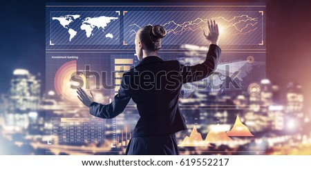 Back view of businesswoman working with virtual panel and night city at background