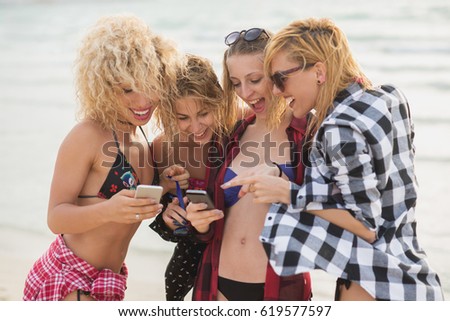 Girlfriends in cool summer look, chilling at beach, having good time. Standing in the sun.
