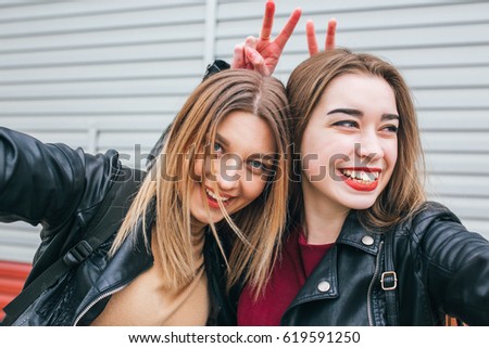 Two young girls taking selfie using smartphone