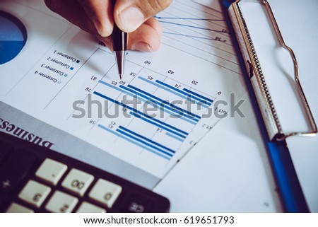 Business meeting, man's hands pointing on charts. Reflection light and flare. Concept image of data gathering and statistical working.

