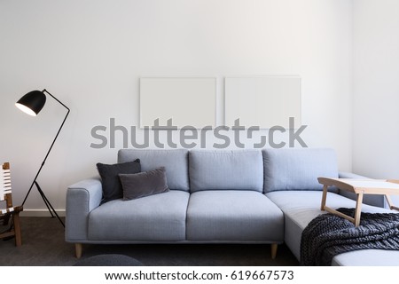 Pale blue linen sofa and blank pictures in a living room