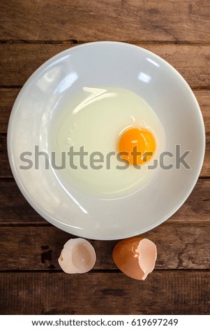 Broken egg in a plate on a wooden table
