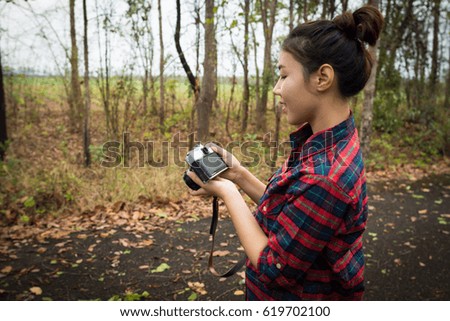 Young woman holding an ancient camera taking nature on a forest road.