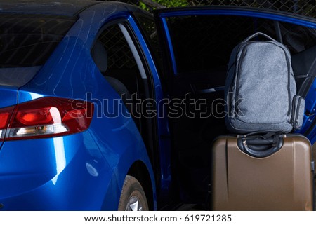Loading luggage in modern blue car with open back door