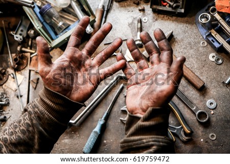 A picture of dirty hands of a guy from the garage. Hard and dirty work is behind him. 