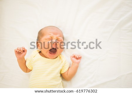 newborn baby yawns,Two week old.Newborn baby yawning lying on bed.  Royalty-Free Stock Photo #619776302