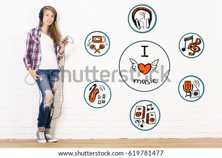 Pretty young girl listening to music in interior with sketch on brick wall. I love music concept