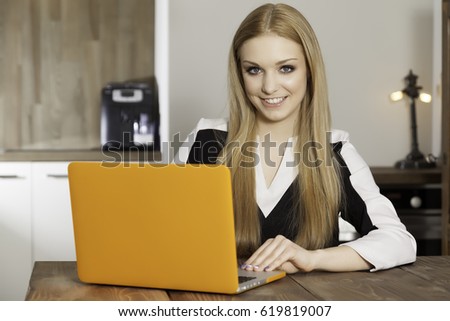 Portrait of a smiling young woman with laptop in the kitchen