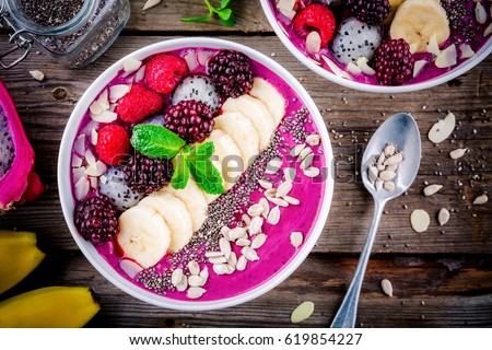 Healthy breakfast bowl: blueberry smoothie with banana, raspberry, pitaya, blackberry, almonds, sunflower and chia seeds Royalty-Free Stock Photo #619854227