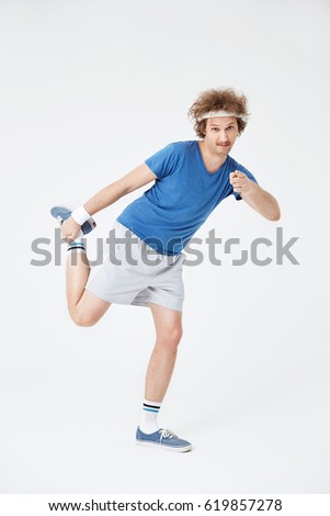 Retro guy stretching right leg holding foot with right hand