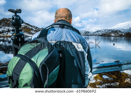 Travel photographer doing pictures outdoor at evening time. Lofoten islands. Beautiful Norway landscape. 
