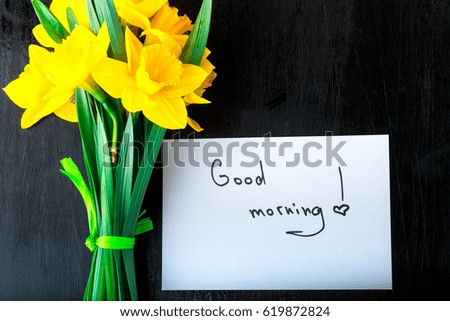 Yellow daffodil flowers and quotes good morning on white rustic table. Mothers day or Womens day. Greeting card. Top view. Love