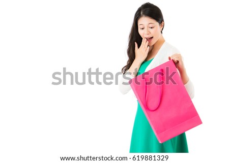 surprised woman looking pink shopping bag on the white wall background over empty  area finding excited thing in the sack on copyspace.
