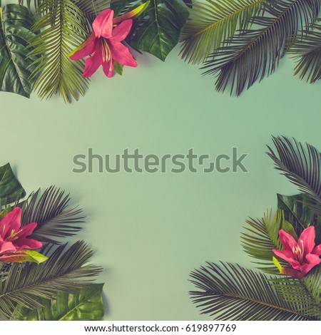Creative nature layout made of tropical leaves and flowers on sky blue background. Flat lay. Summer concept.