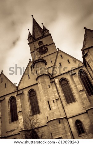 The Lutheran Cathedral in the old medieval city of Sibiu, Romania, under a storm sky. Aged photo look.
