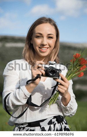 A young woman with a camera and a bouquet of poppies