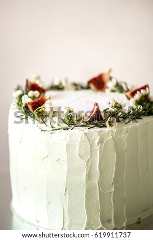 Sponge cake with matcha tea cream and the layer of strawberry confit decorated with fresh figs and flowers