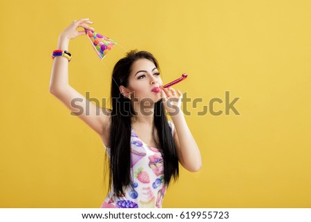 portrait of funny woman in birthday hat and pink shirt on yellow background. Celebration and party. Having fun.