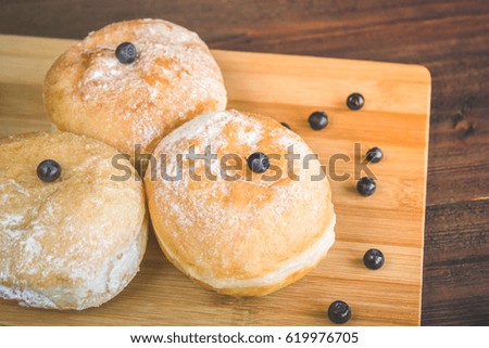 blueberry donuts sprinkled with icing sugar on wooden background.