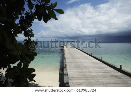 wooden pier stretching out into ocean with clouds in background
