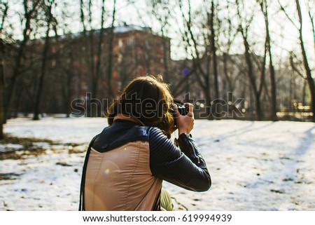 Girl is walking in the spring park in the sun and making photos