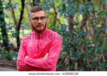 Handsome young man with a beard in a outdoor park setting.
