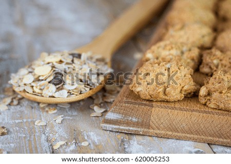 Muesli on wooden spoon and fresh biscuits with cereals on a wooden table. Homemade cakes on wooden rustic table.