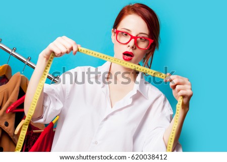 photo of beautiful young woman with centimeter near clothes on the wonderful blue background