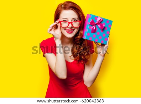 photo of beautiful young woman holding cute gift on the wonderful yellow studio background