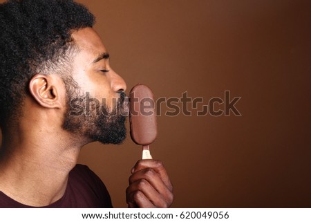Beautiful afro man with ice-cream in front of a brown background