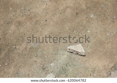 a triangle piece of concrete like a rock on the dirt floor