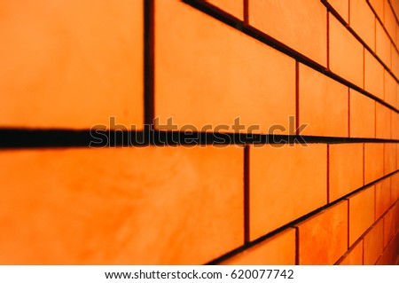Angle side view of Orange-red brick wall background with a layer of red paint with blurred long-range - texture pattern for continuous replicate. shallow depth of field