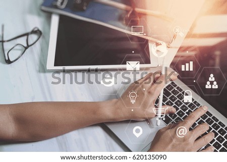 businessman working with digital tablet and laptop computer on wooden desk in modern office with virtual icons interface