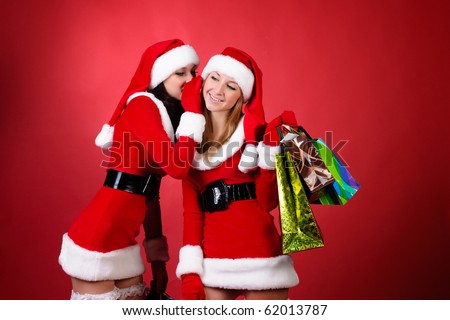 wo happy young Santa girl talking over red background .