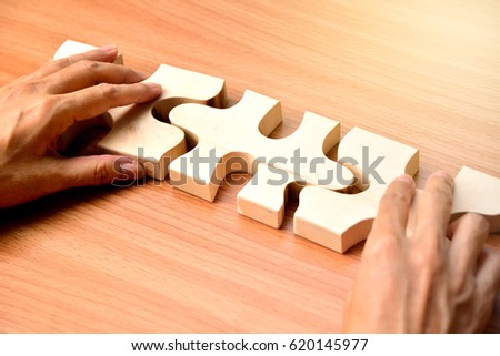 hand holding wood jigsaw piece texture pattern on wood table background